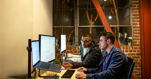 An image oft two male developers working and collaborating in an casual enterprise office