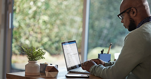 Male working remotely from his home office on a Dell Latitude 13 device, running Microsoft Word