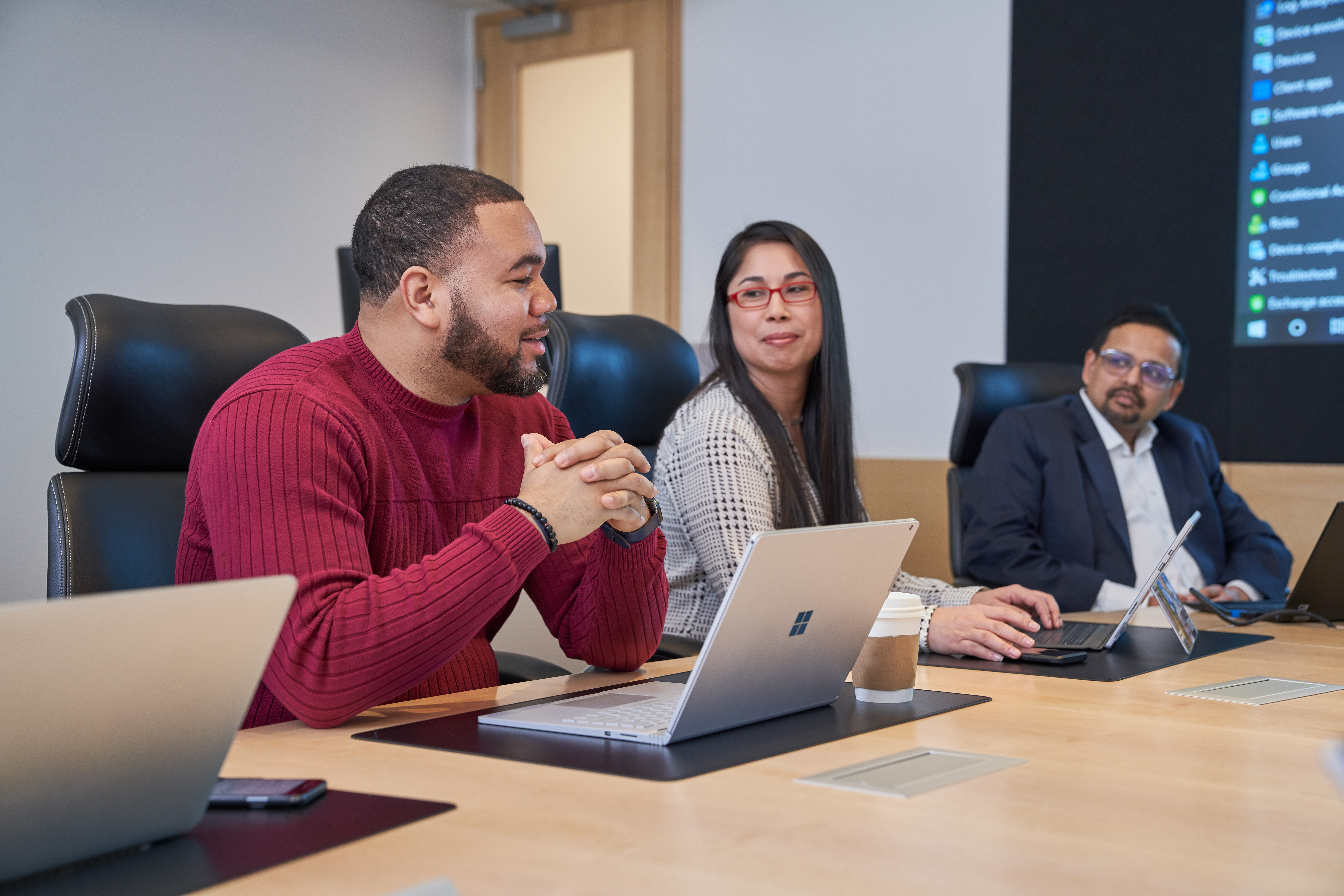 Group of people at a conference table with laptops who appear to be have a healthy and positive discussion or meeting