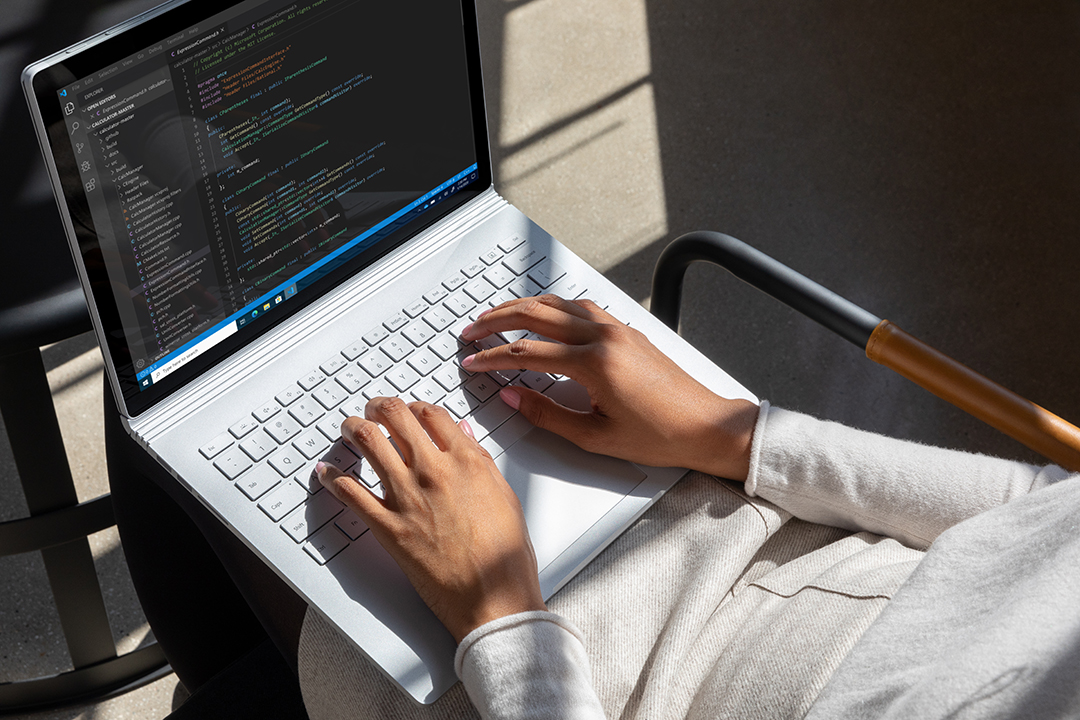 Commercial contextual lifestyle image of adult female working in Azure on Surface Book 3 inside
