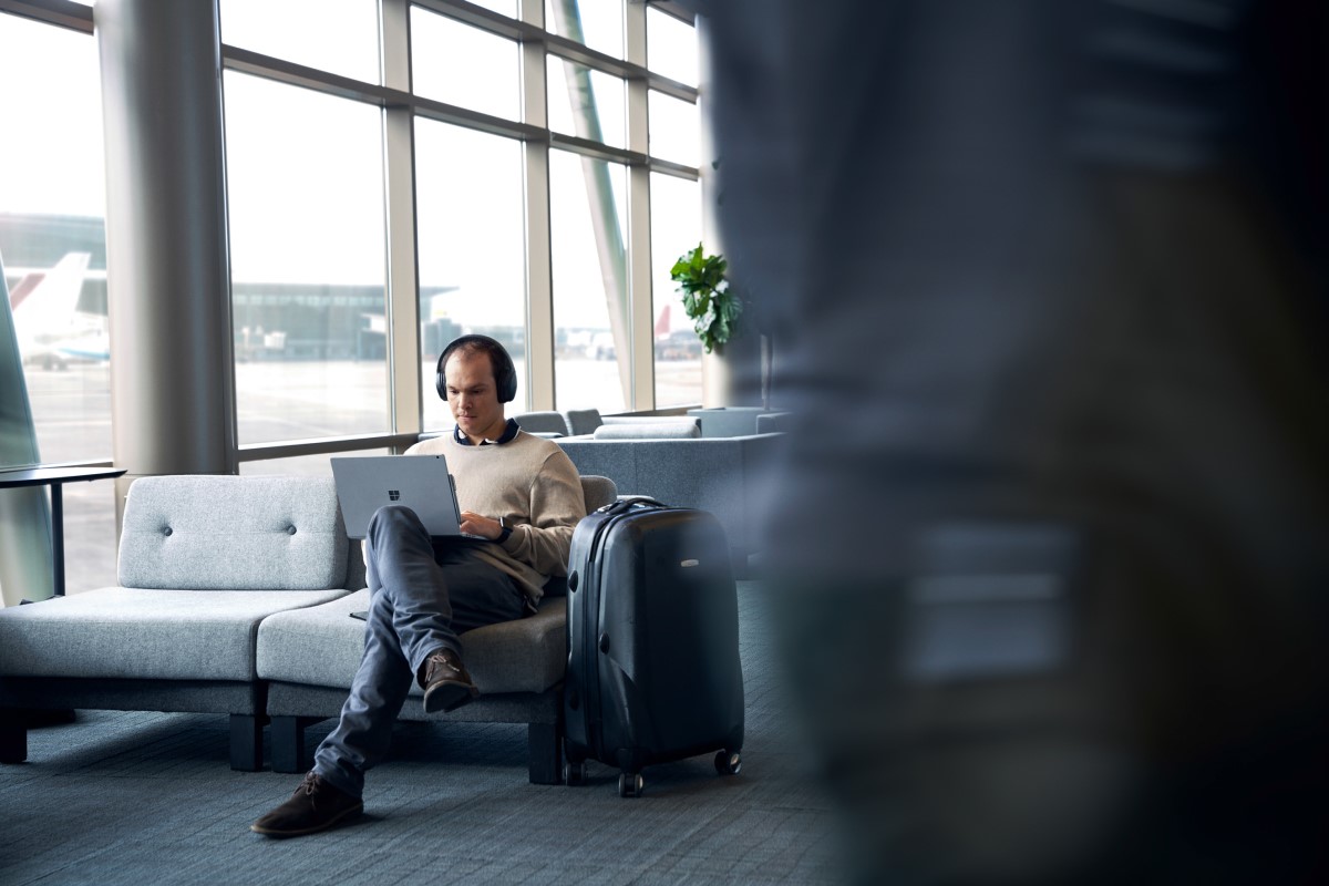 Adult male sitting in airport terminal working on his laptop