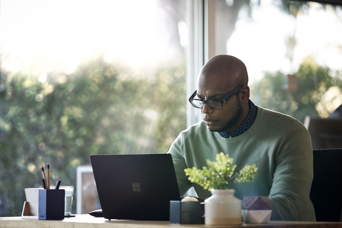 Male working remotely from his home office on Surface Laptop 2 device