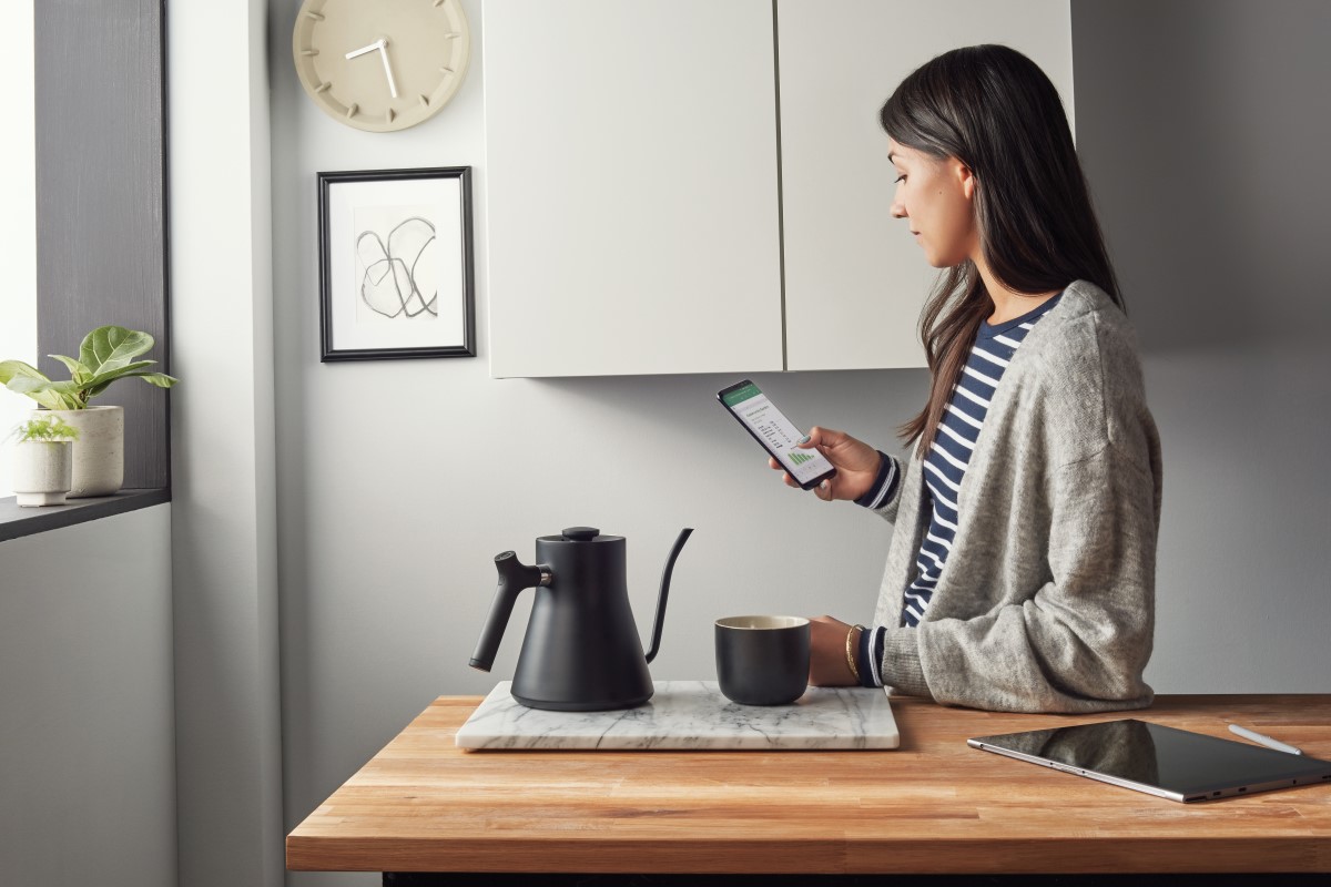 Woman working in Excel on Android phone inside in the kitchen