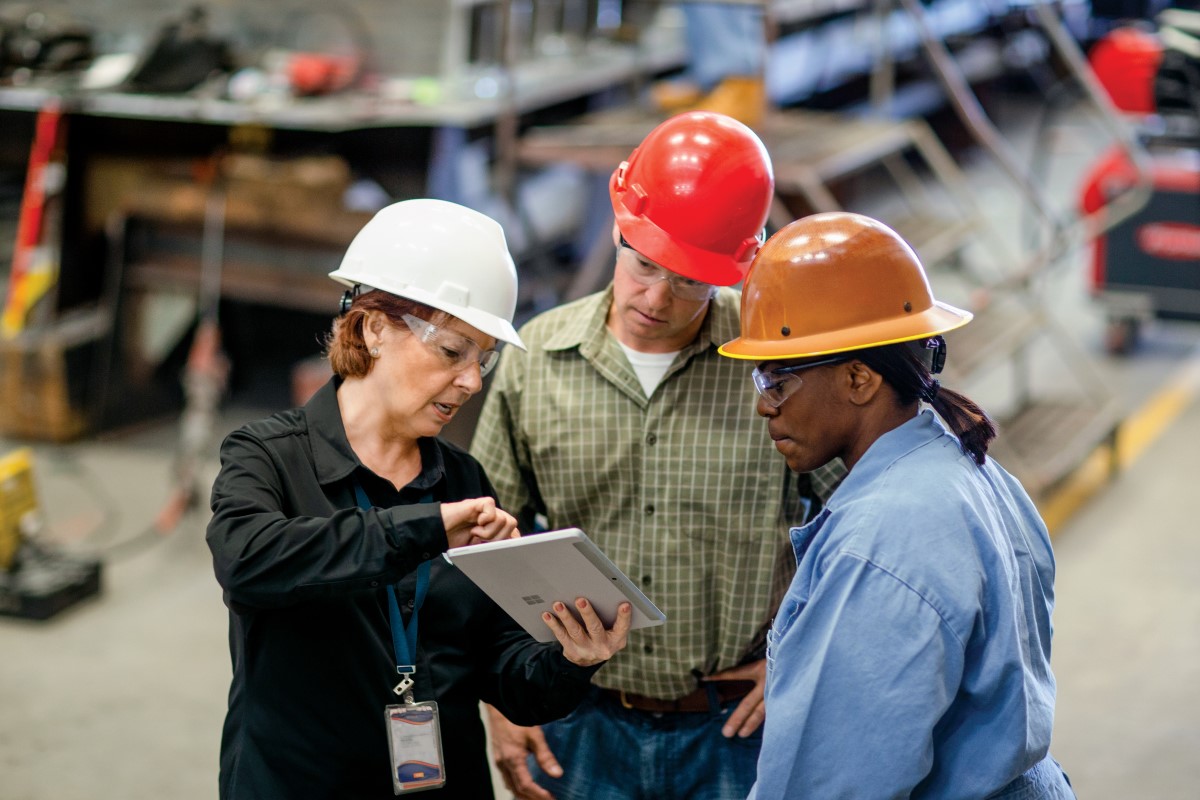 CEO of large manufacturing company discussing a project with operations manager and foreman