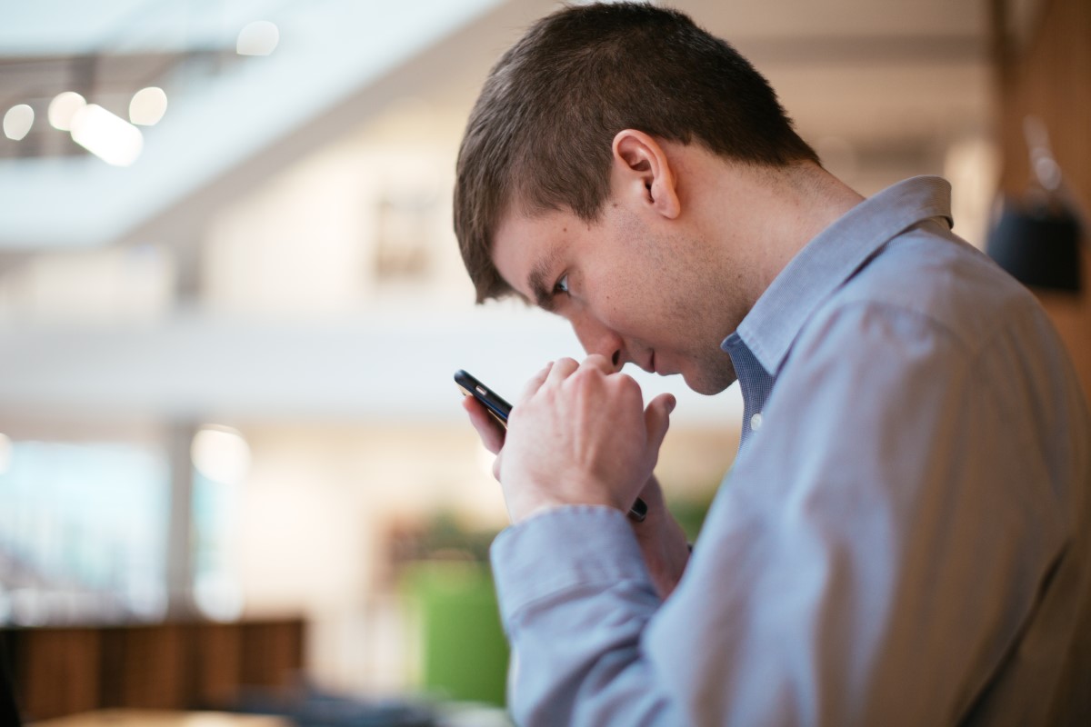 Man with low vision holds a mobile phone close to his face in order to view the screen