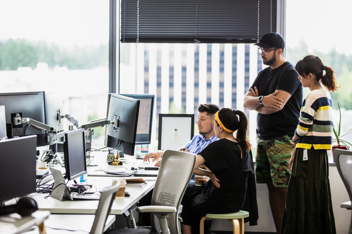 A group of designers collaborate on a project together using shared screen in U.S. office