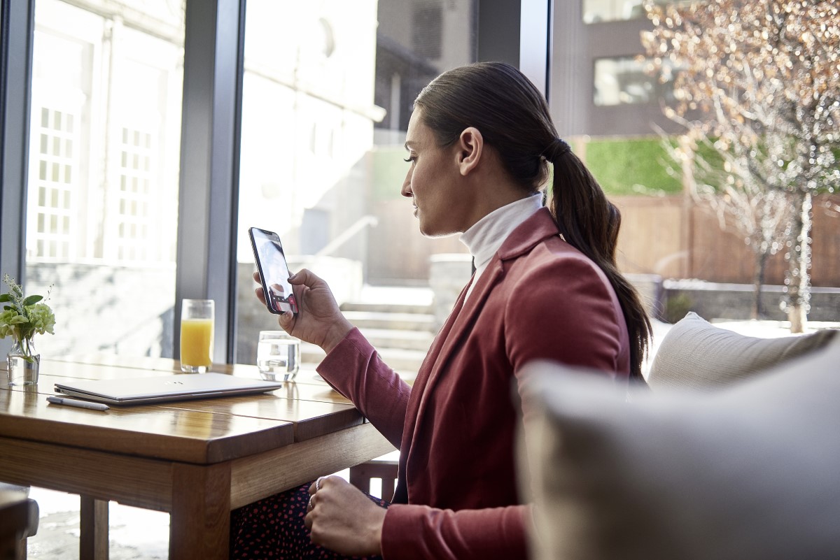 Female small business executive at table on using Microsoft Teams on an iPhone