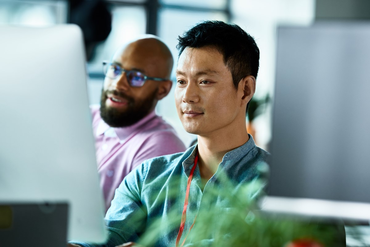 Two male co-workers looking at computer screen and concentrating