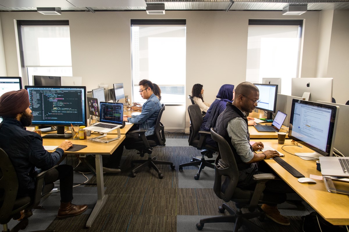 Female and male developers at at work; coding individually and sometimes collaboratively in an enterprise office space using Visual Studio for Mac