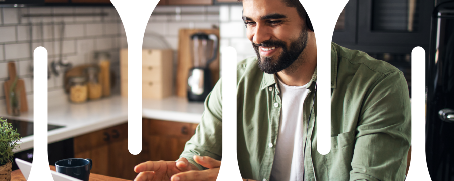 Adult male working from home at kitchen table with headphones on and talking with his hands