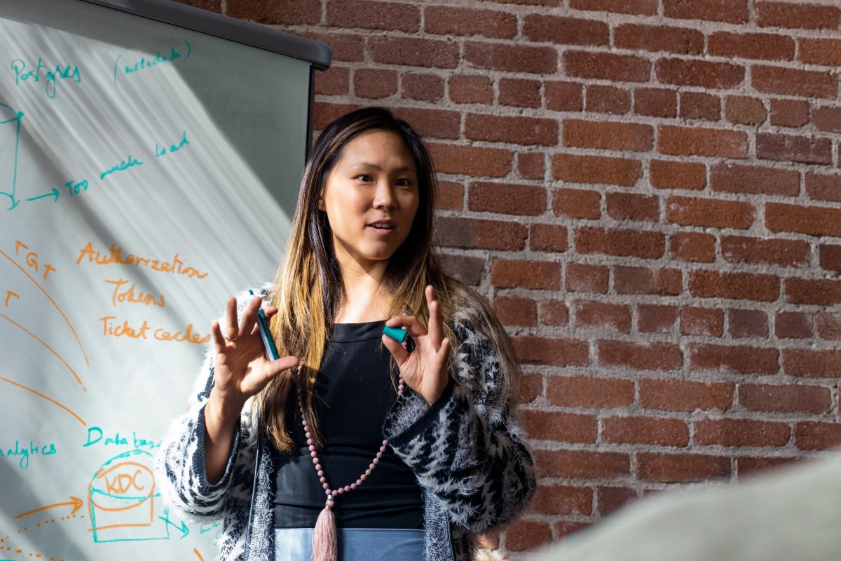 Female developer speaking in front of a white board during team stand up meeting