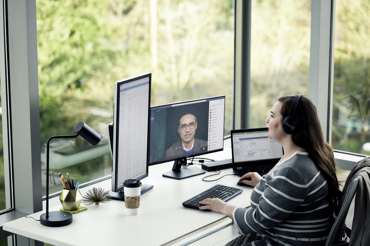 Adult female working from home using multiple desktop screens