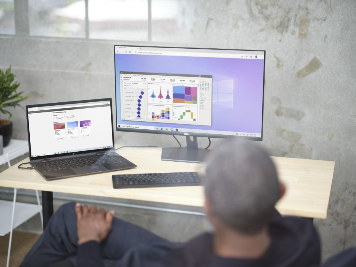 Man sitting at a desk viewing Power BI and Welcome Screen within Windows 365