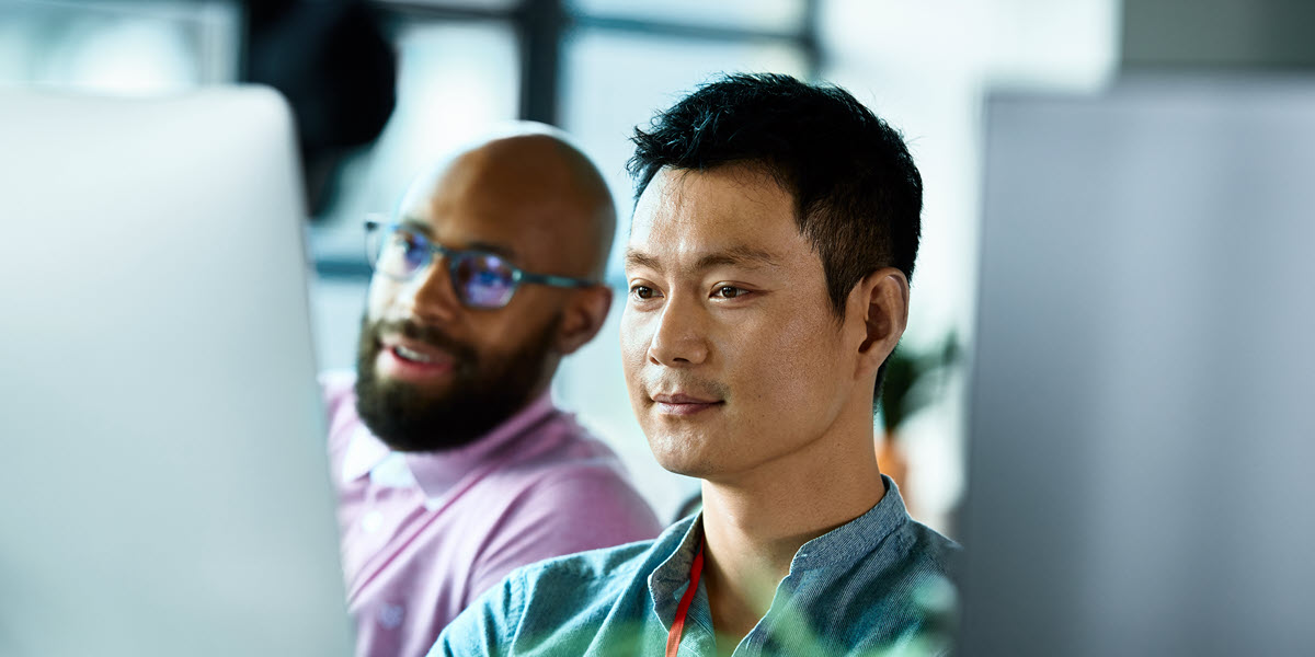 Two adult male IT professionals looking at a computer screen