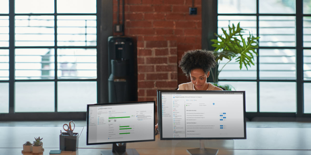 Individual at work behind two computer screens