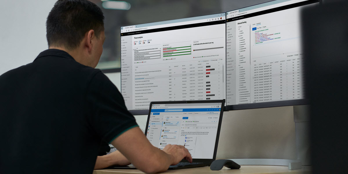 Security practitioner in front of two computer screens, working on their laptop to investigate threats
