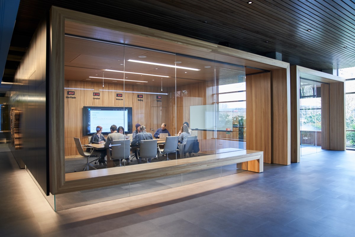 Outside of a conference room or board room meeting including people sitting around table in a room with international time clocks