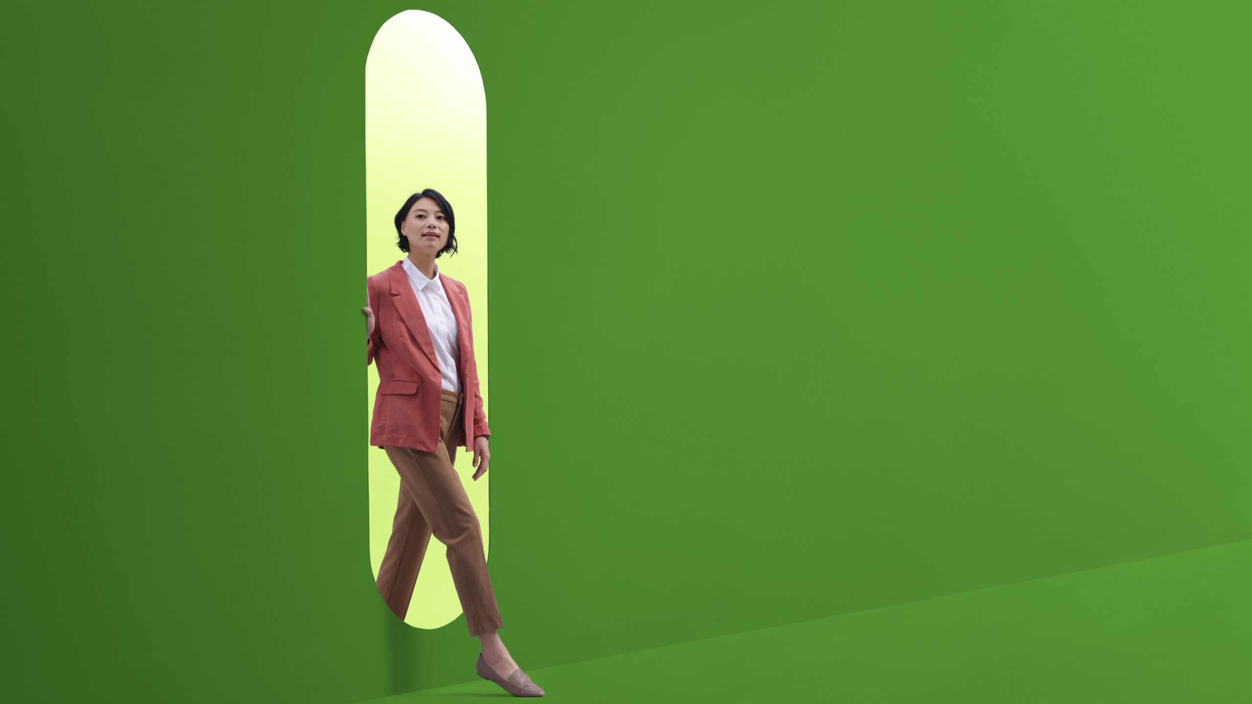 Woman entering a green room through an oval with lighter green behind her