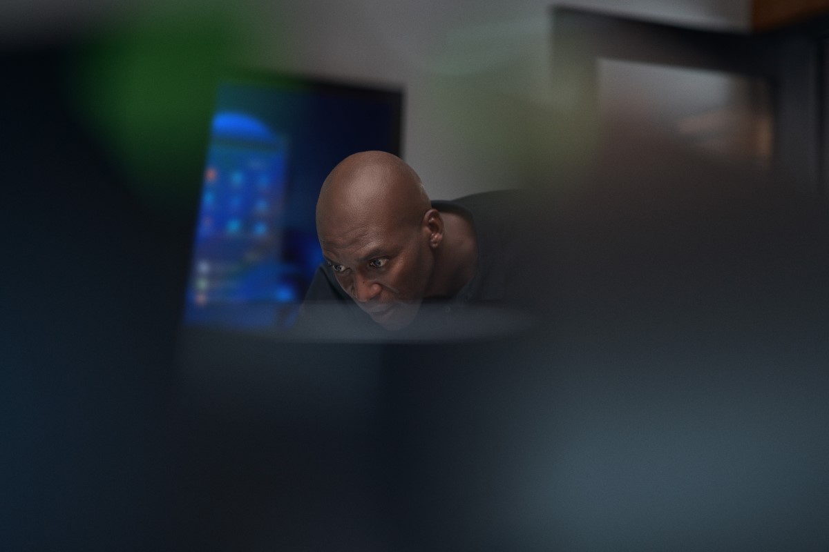 Employee leaning down, working at computer station