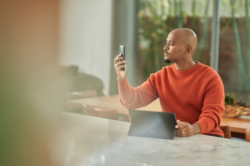 Seller completing multi-factor authentication via facial recognition on a mobile phone before working from home