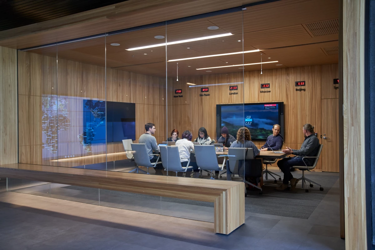 Conference room or board room meeting with people sitting around table in a room with international time clocks, and a map projection