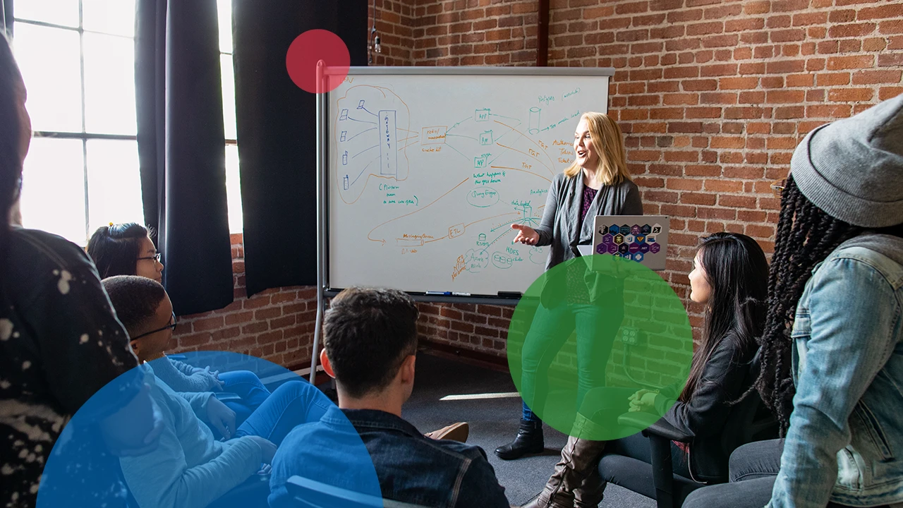 A woman standing in front of a whiteboard giving a presentation