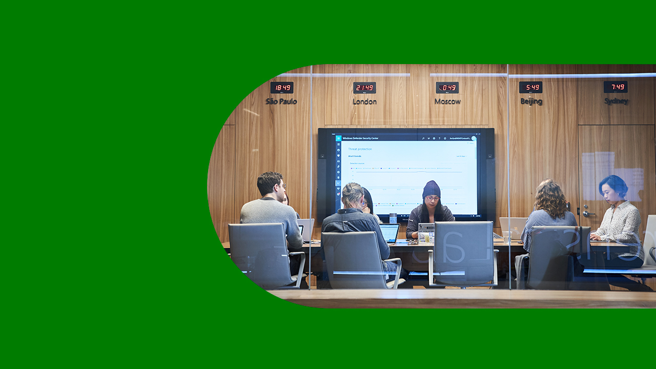 Looking into a conference room or board room meeting including people sitting around table in a room with international time clocks