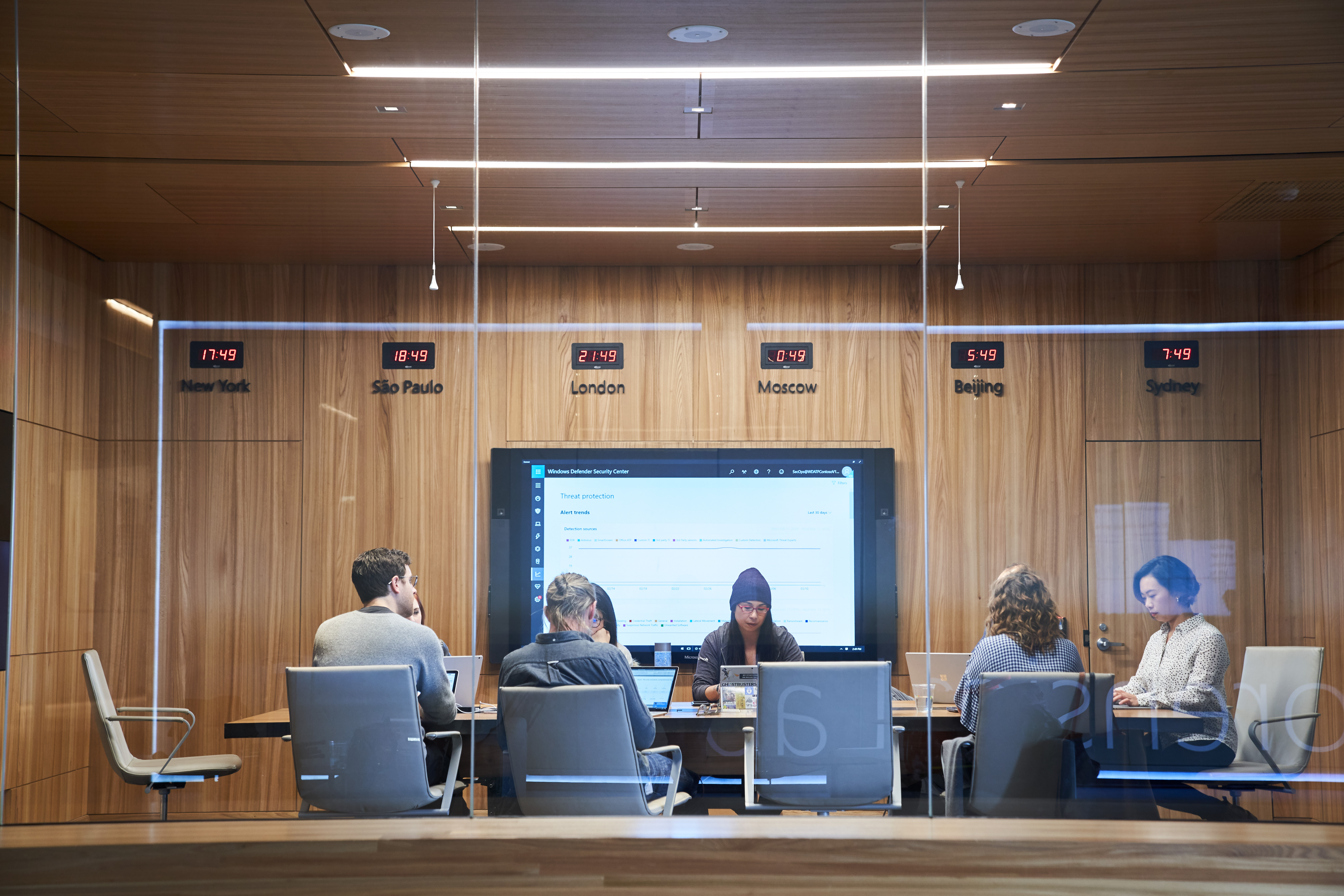Looking into a conference room or board room meeting including people sitting around table in a room with international time clocks