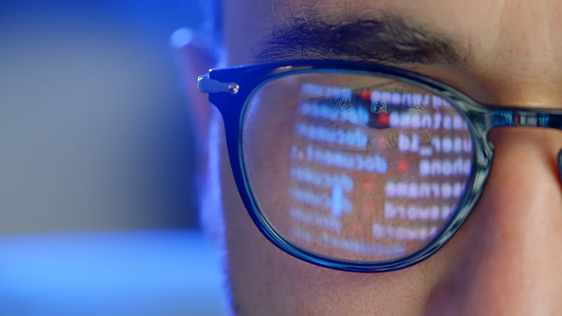 A person wearing glasses with code from a computer screen reflected in the lens