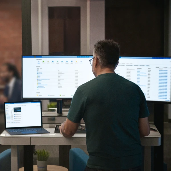 Person working at desk with monitors and laptop.