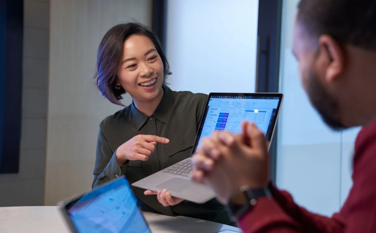 A woman shows a colleague a view of her computer screen