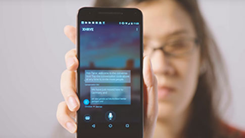 Eine Frau, die ihr Smartphone hochhält und die Translator App im Gesprächsmodus zeigt.