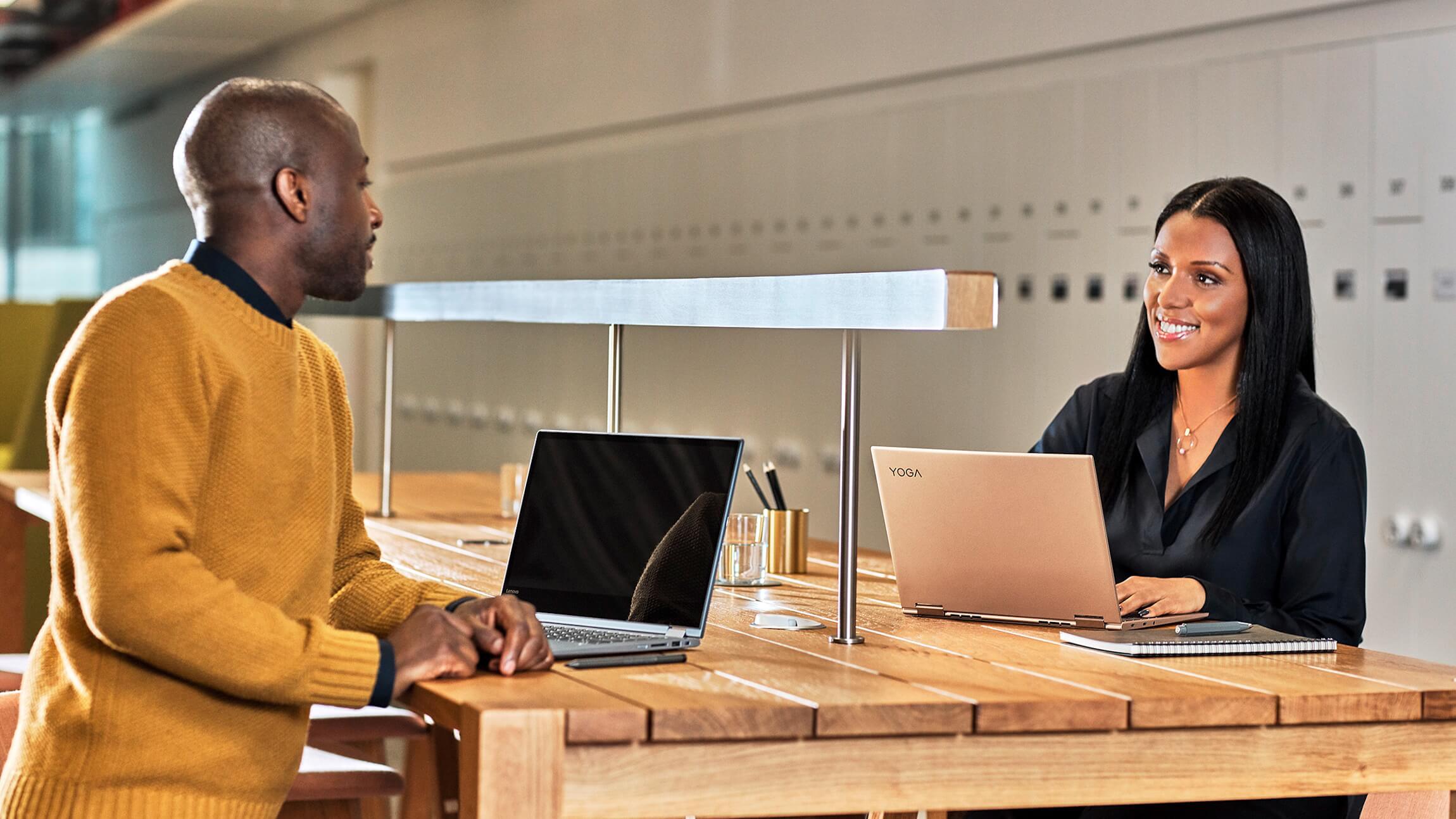 Two people collaborate at a table in a large, open workspace.